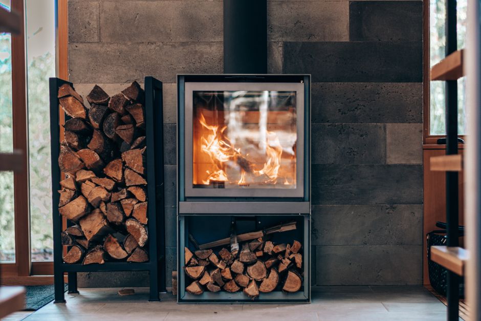 Poêle à bois contemporain en fonctionnement, réserves de bûches rangées de part et d'autre